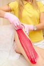 depilation and beauty concept - procedure of hair removing on leg beautiful woman with sugar paste or wax honey and pink