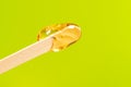 depilation and beauty concept - sugar paste or honey wax for hair removing spatula with wooden framing sticks on a bright green