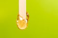 depilation and beauty concept - sugar paste or honey wax for hair removing spatula with wooden framing sticks on a bright green