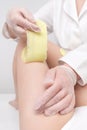 Depilation procedure - cosmetologist hands in gloves removing hair on women leg. Waxing process