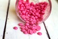 Depilatory pearly pink solid wax beans on wood background.