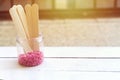 Depilatory pearly pink solid wax beans and wooden stick wood on wood background