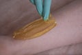 Depilatory Procedure with Sugar Paste. Removing Hair on Women`s legs. Procedure sugaring in a beauty salon. Close Up