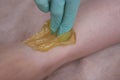 Depilatory Procedure with Sugar Paste. Removing Hair on Women`s legs. Procedure sugaring in a beauty salon. Close Up