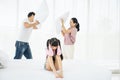 Depress asian girl child cover her ears with parents having argument using pillow fight together in the background Royalty Free Stock Photo