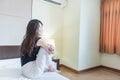 depress woman sitting on bed in room with hand around her knee