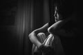 depress woman sitting on chair in room near window in white tone