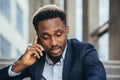 Depressed african american businessman telling sad news talking on cell phone sitting on office stairs in business suit Royalty Free Stock Photo