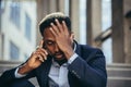 Depressed african american businessman telling sad news talking on cell phone sitting on office stairs in business suit Royalty Free Stock Photo