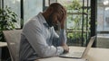 Depressed African american ethnic mature businessman stressful sick man sit in office with laptop read papers documents Royalty Free Stock Photo