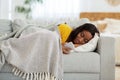 Depressed African American lady lying on couch with smartphone and reading upsetting message, indoors Royalty Free Stock Photo