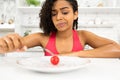 Depressed afro lady looking at tiny tomato on a plate