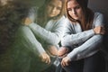 Depressed/anxious young woman sitting by a large window