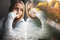 Depressed/anxious young woman sitting by a large window