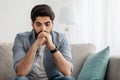 Depressed arab man having problems, thinking while sitting on couch at home, empty space Royalty Free Stock Photo