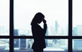 Depressed asian business woman standing at windows with city view background Royalty Free Stock Photo