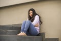 Depressed Asian Chinese student woman or bullied teenager sitting outdoors on street staircase overwhelmed and anxious feeling