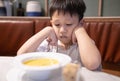 Depressed asian kid boy with anorexia,don`t have appetite,child kindergarten bored with food or boredom,refusing to eat vegetable