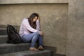 Depressed Asian Korean student woman or bullied teenager sitting outdoors on street staircase overwhelmed and anxious feeling