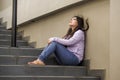 Depressed Asian Korean student woman or bullied teenager sitting outdoors on street staircase overwhelmed and anxious feeling