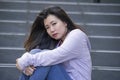 Depressed Asian Korean student woman or bullied teenager sitting outdoors on street staircase overwhelmed and anxious feeling