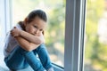 Depressed Asian Little Girl Sitting Near Window At Home Royalty Free Stock Photo