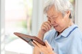 Depressed asian senior woman holding a picture frame and watching old photographs of family at home,devastated elderly people