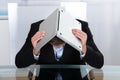 Depressed businessman hiding under his laptop Royalty Free Stock Photo
