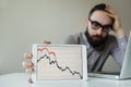 Depressed businessman leaning head below bad stock market chart Royalty Free Stock Photo