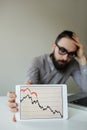 Depressed businessman leaning head below bad stock market chart Royalty Free Stock Photo