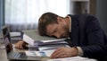 Depressed businessman lying on pile of folders, deadline pressure, exhaustion