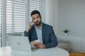 Depressed businessman man counting euro money working on computer at office desk, using smartphone and looking at camera Royalty Free Stock Photo