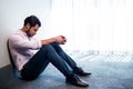 Depressed businessman sitting against a wall and looking down Royalty Free Stock Photo