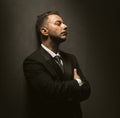 Depressed businessman stands in dark room. Sad man stands with his eyes closed and arms crossed, leaning his back Royalty Free Stock Photo