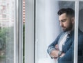 Depressed caucasian man losing job and heartbroken, alone near window Royalty Free Stock Photo