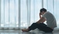 Depressed caucasian man losing job and heartbroken at same time sitting alone near window in dark at evening time with low light Royalty Free Stock Photo