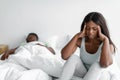 Depressed despaired sad young african american female suffers from snoring sleeping guy, lady covers ears