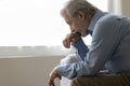 Depressed elder retired man sitting on home couch