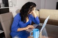 A depressed executive reading the reports of her work group, dressed in blue and with a blue coffee cup in of Blue Monday.