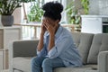 Depressed exhausted unhappy young woman sits on home couch hiding face in hands feel cheated alone. Royalty Free Stock Photo