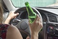 Depressed female driver drinking whiskey from a bottle getting shocked driving a car. Woman drinking alcohol while driving the car