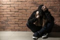 Depressed female junkie near brick wall. Concept of addiction Royalty Free Stock Photo