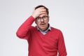 Depressed and frustrated young man in red sweater touching head Royalty Free Stock Photo