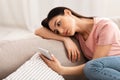 Frustrated woman checking mobile phone sitting on the couch Royalty Free Stock Photo