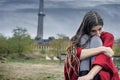 Depressed girl in a red poncho sitting on a bench alone