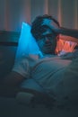 Depressed insomnia man holding his head on a bed late at night with Black Medical pills for stress and suicide concept Royalty Free Stock Photo
