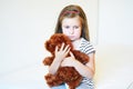 Depressed little girl hugging teddy bear