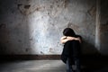 Depressed and lonely girl sitting alone in a spooky abandoned dirty old room on the wooden floor feeling miserable Royalty Free Stock Photo