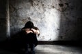 Depressed and lonely girl sitting alone in a spooky abandoned dirty old room on the wooden floor feeling miserable Royalty Free Stock Photo