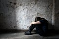 Depressed and lonely girl sitting alone in a spooky abandoned dirty old room on the wooden floor feeling miserable Royalty Free Stock Photo